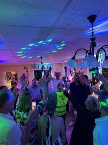 Jubelnde Gäste tanzen und feiern auf einer Hochzeitsparty mit DJ in Berlin