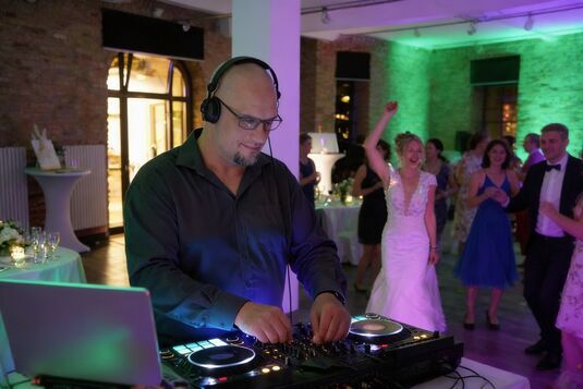 DJ Olaf beim Auflegen auf einer Hochzeit in Berlin, während Gäste und das Brautpaar tanzen und feiern